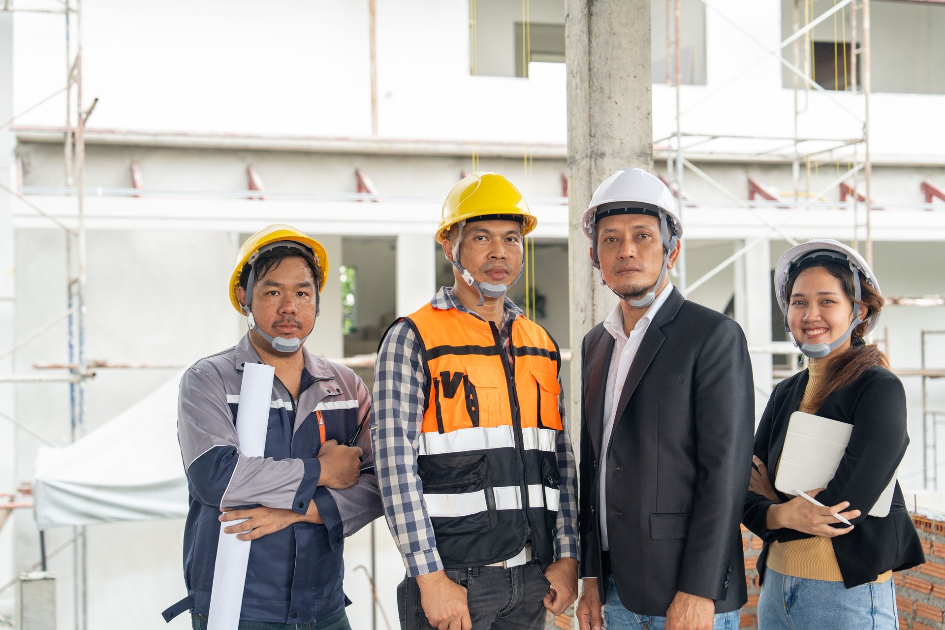 Construction teamwork, Engineer building, Civil Engineer, Contractor and Architect standing with arms crossed ware hard hat, construction plan blueprint in construction site.