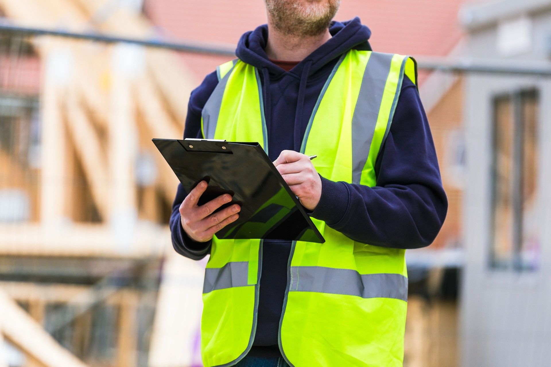 Construction worker examining documents on clipboard